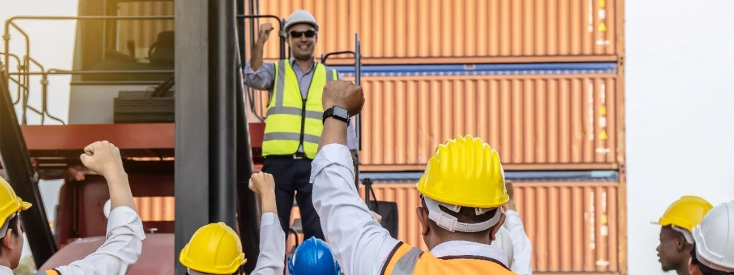 Engineers wearing helmets and holding fists in the air