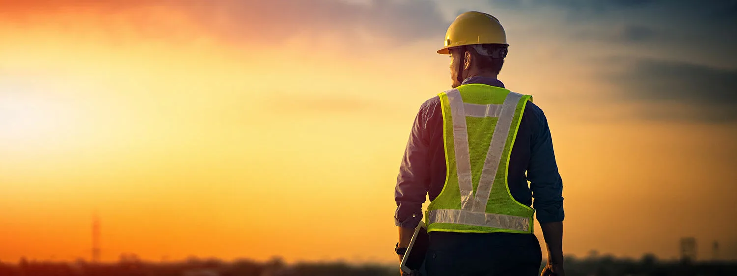 An engineer working at sunset with yellow vest