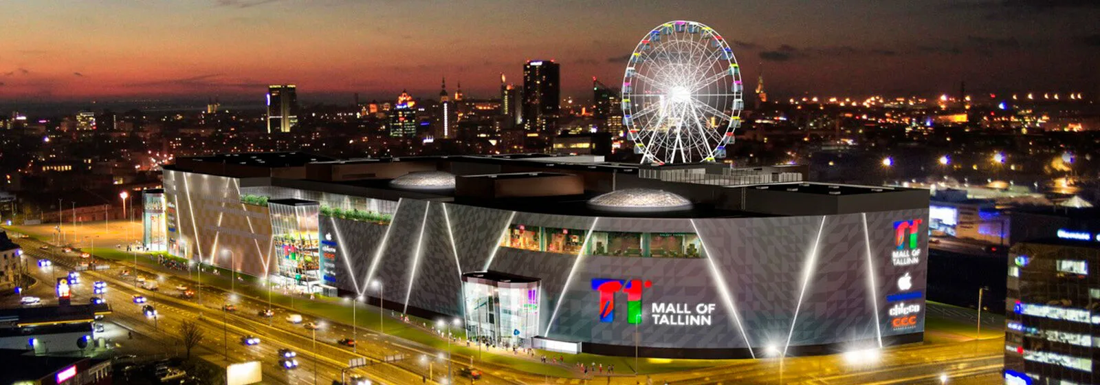 Night view of Mall of Tallinn with illuminated exterior and Ferris wheel in the background, showcasing vibrant city lights