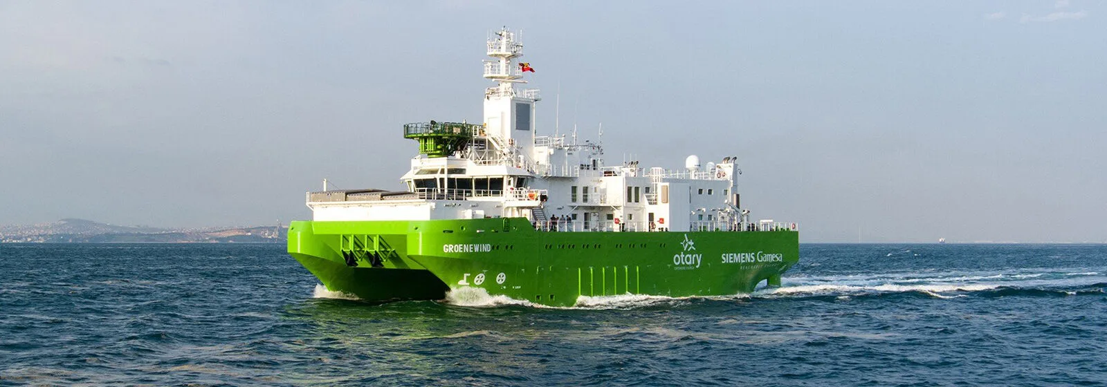Green offshore vessel 'GROENEWIND' sailing at sea with Otary and Siemens Gamesa logos and communication equipment on deck