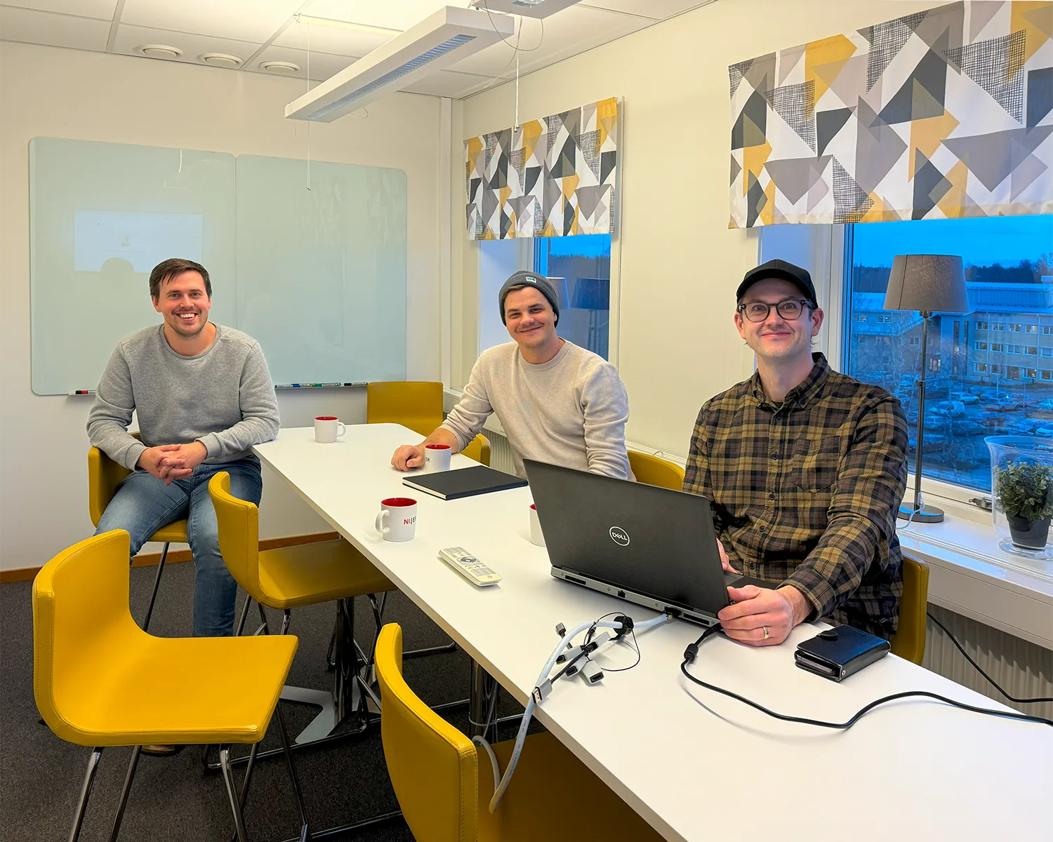 Three engineers in their office space smiling at the camera over Cadmatic software